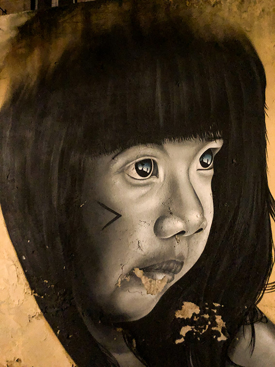 une oeuvre peinte sur un mur de Lx Factory, représentant le visage d'une fille aux cheveux noirs