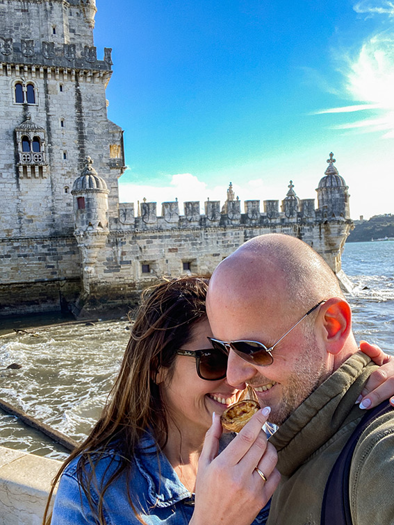 Joli couple dégustant un pastel de Nata devant la Tour de Belém lors d'une belle journée ensoleillée