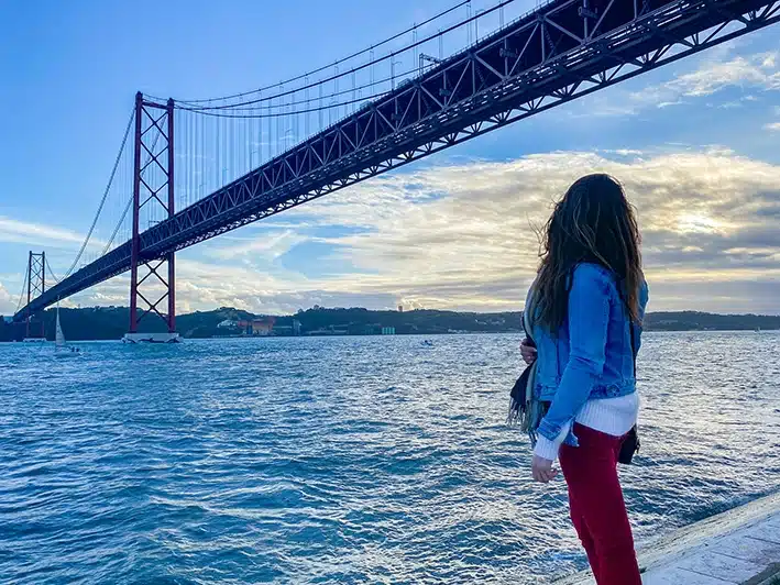 une jeune femme admire le pont du 25 avril à Lisbonne