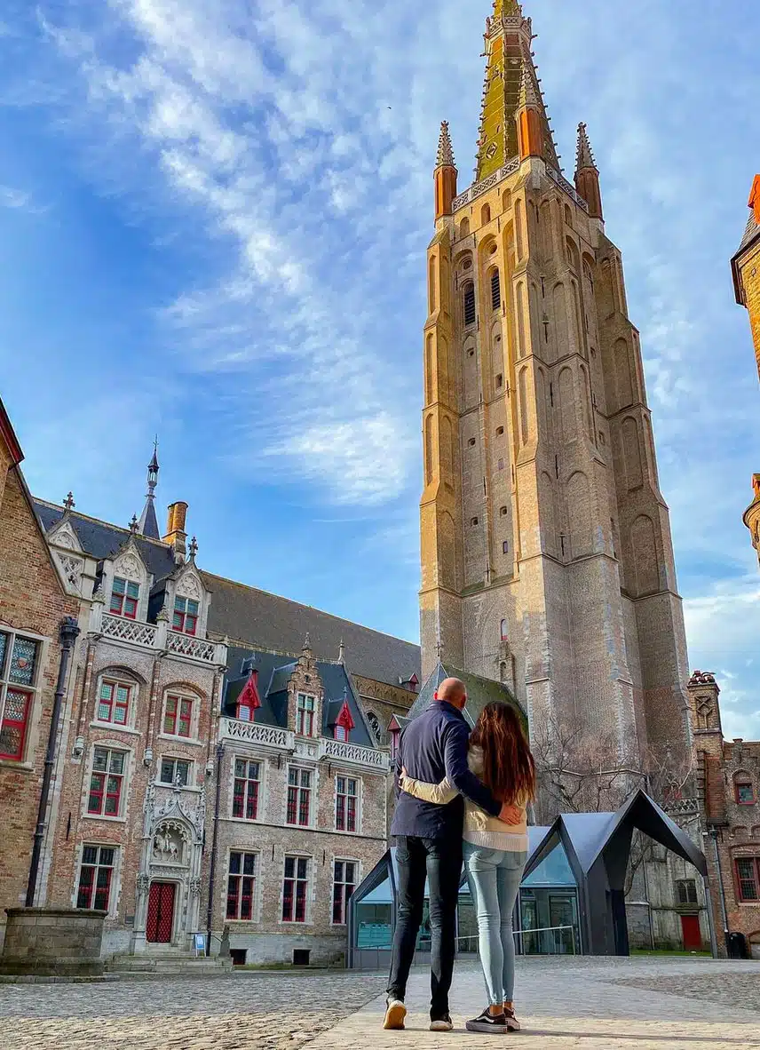 un jeune couple contemple la flèche de l'église Notre -Dame de Bruges.