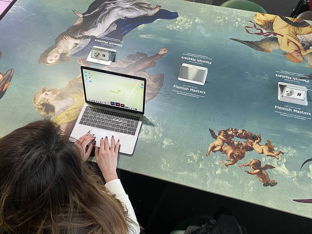 Une jeune femme travaille sur son ordinateur Apple en tant que digital nomad dans le terminal de Brussels Airport.