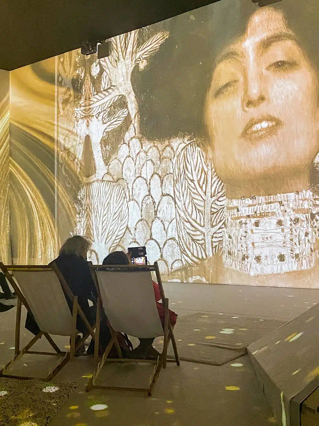 deux personnes dans des transats regardent le show mapping vidéo à l'exposition Klimt de Bruxelles