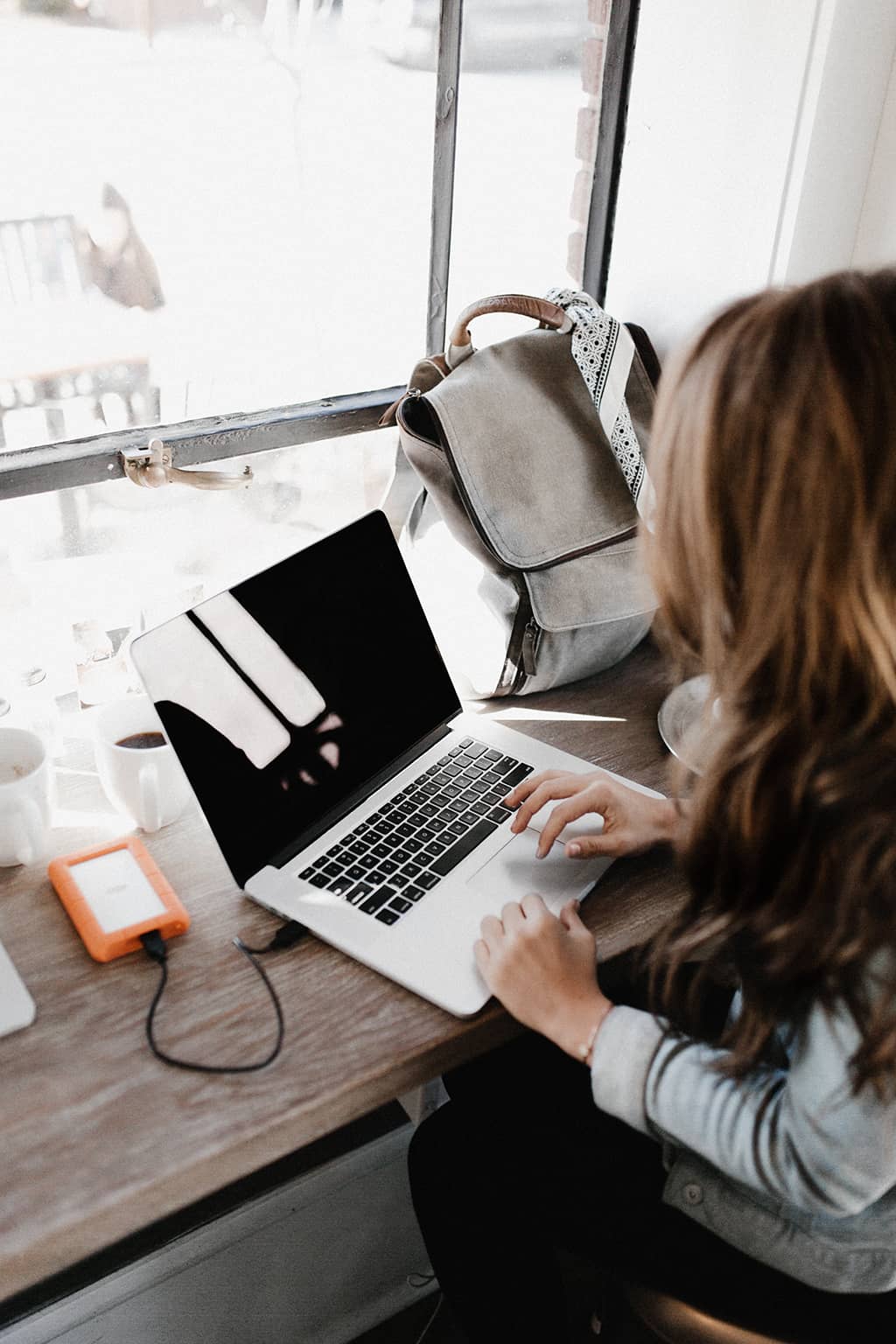 une jeune nomade digitale aux longs cheveux bruns bosse sur son ordinateur portable dans un espace de coworking