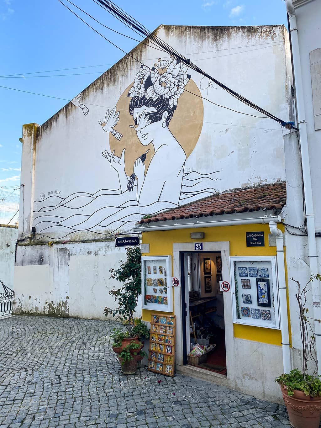 Petite boutique souvenir et streetart sur une façade blanche dans le quartier de l'Alfama à Lisbonne
