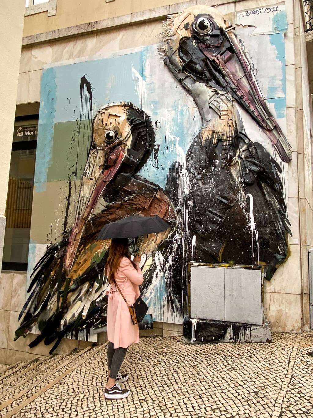 Jeune femme admirant une oeuvre de l'artiste portugais, Bordalo II, au pied de l'ascenseur de Santa Justa à Lisbonne