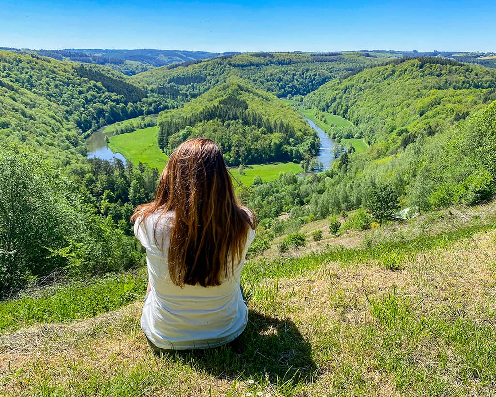 une jeune femme assise dans l'herbe profite de la vue sur le Tombeau du Géant à Botassart