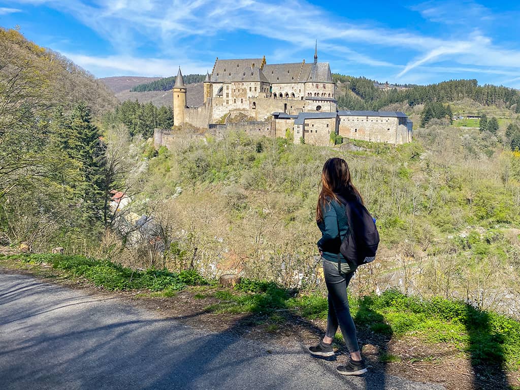 Une jeune femme admire le Château de Vianden depuis la colline opposée au Luxembourg