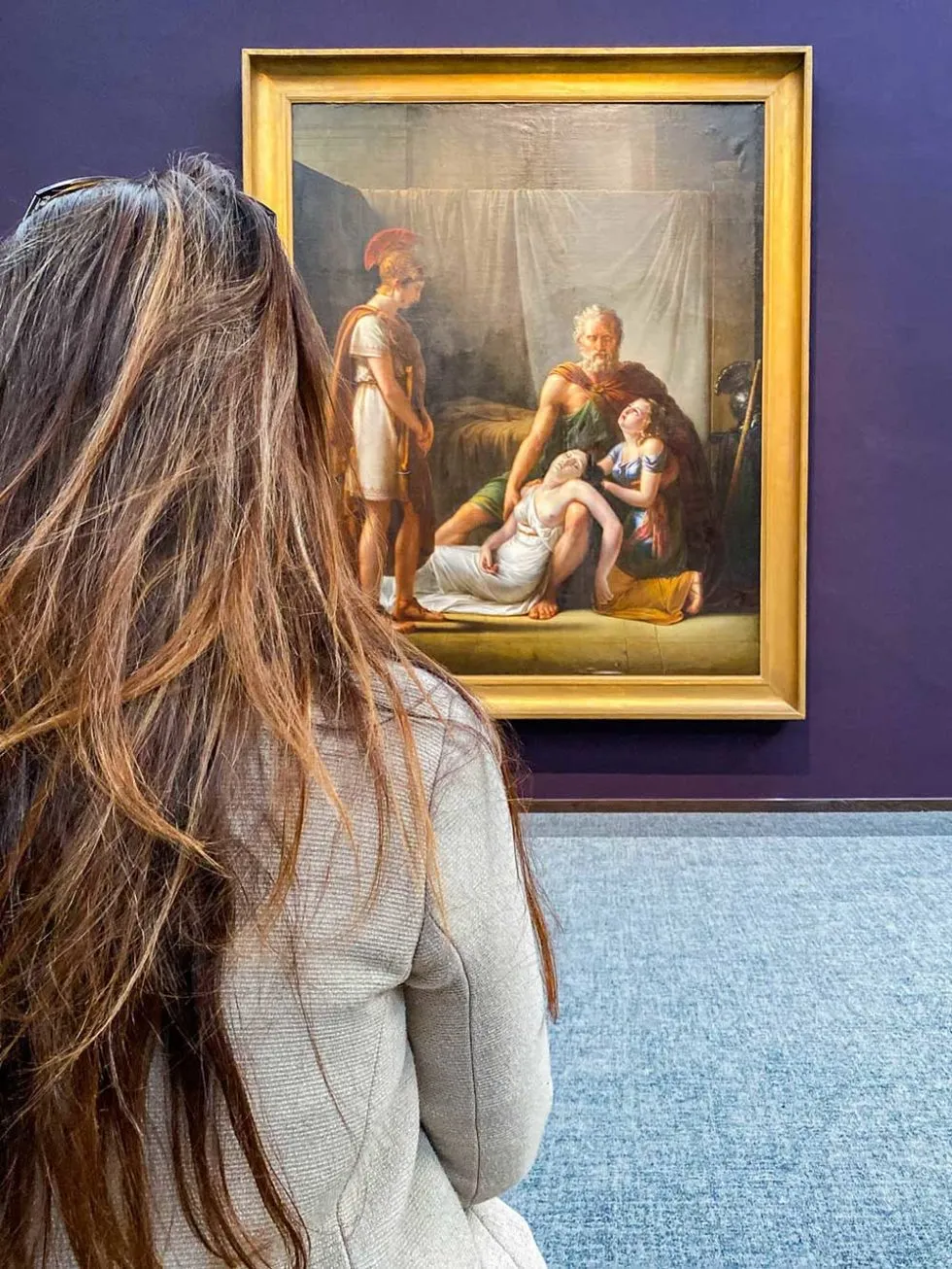 une jeune femme regarde un tableau au muée Groeninge de Bruges. Une visite incontournable lors de votre week-end à Bruges.