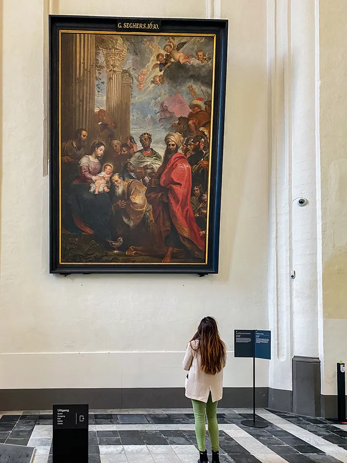 Une jeune femme admire une peinture dans l'église Notre-Dame de Bruges.