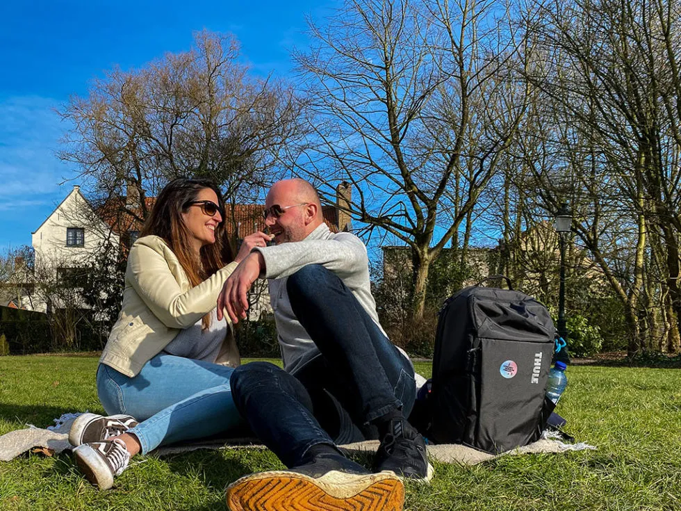 Un jeune couple déguste du chocolat dans le Minnewaterpark lors d'un week-en en amoureux à Bruges