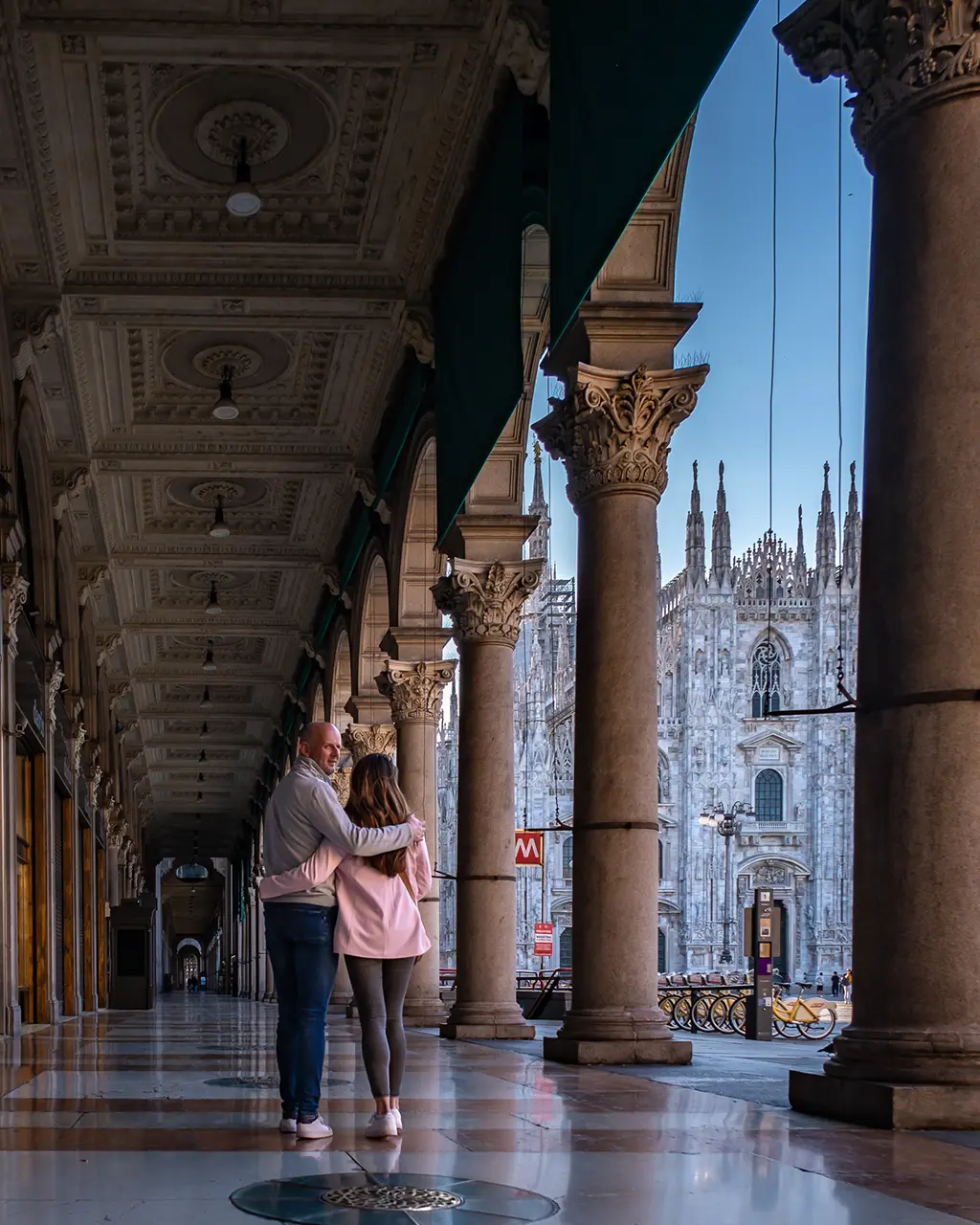 Couple marchant sous les arcades devant le Duomo de Milan