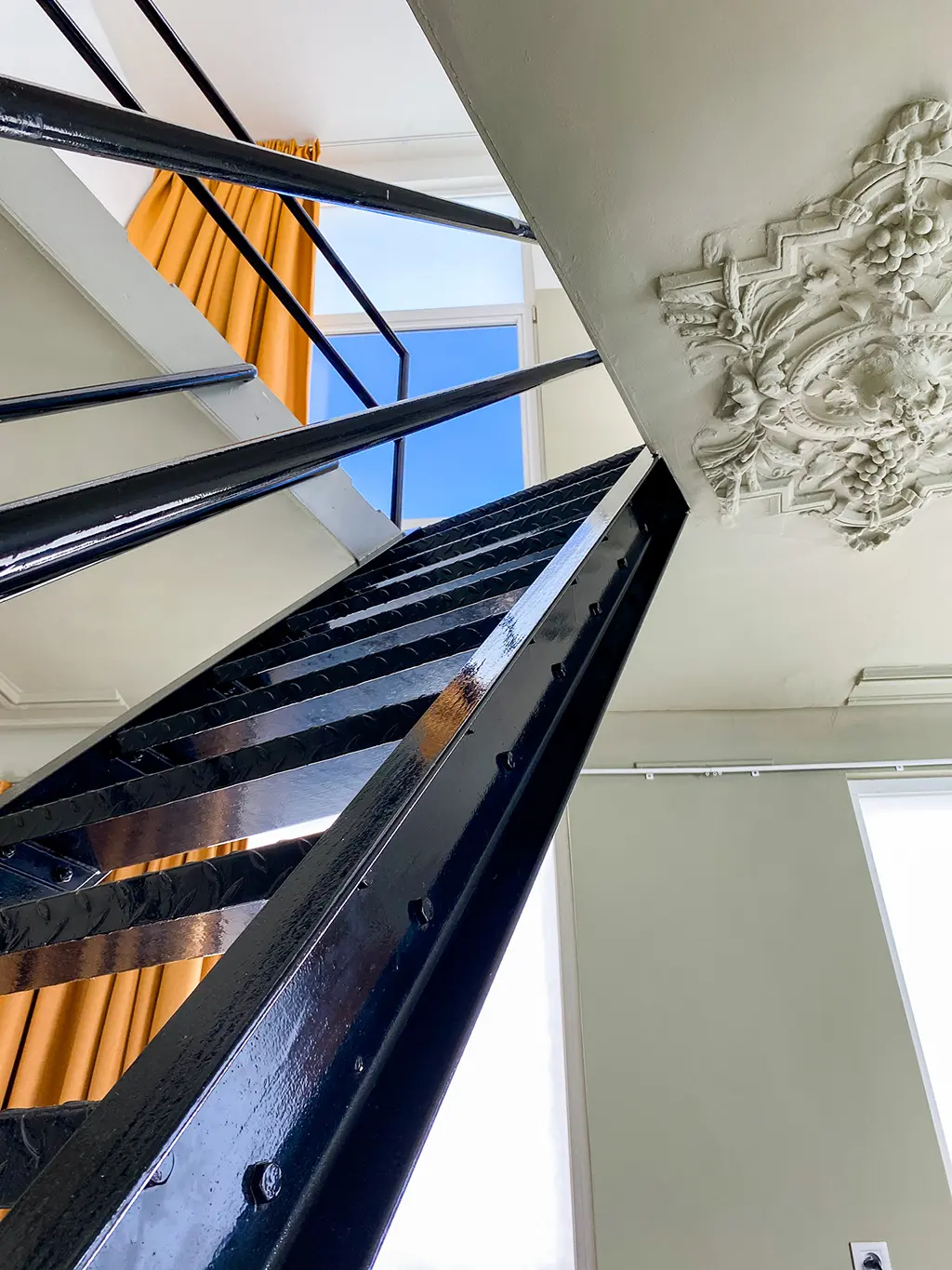 Escalier noir menant à la chambre dans le duplex SHWAY lors de notre week-end en amoureux à Anvers.