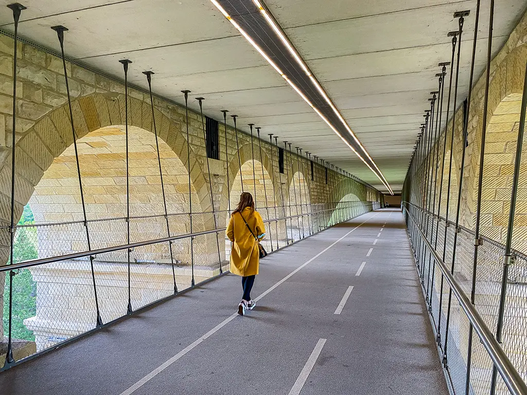 Une jeune femme se promène dans la passerelle sous le Pont Adolphe à Luxembourg.
