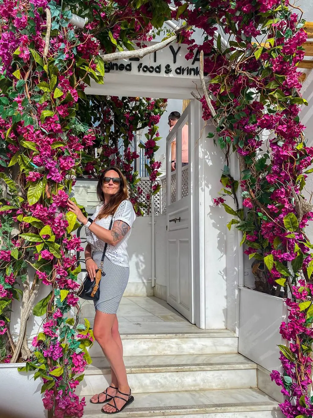 Une jeune femme pose à l'entrée d'un restaurant sur l'île de Santorin