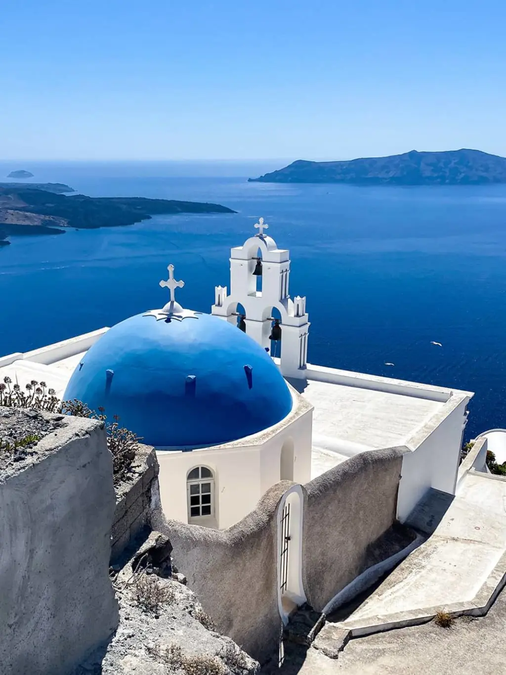 une chapelle au toit bleu surplombe la mer sur l'île de Santorin