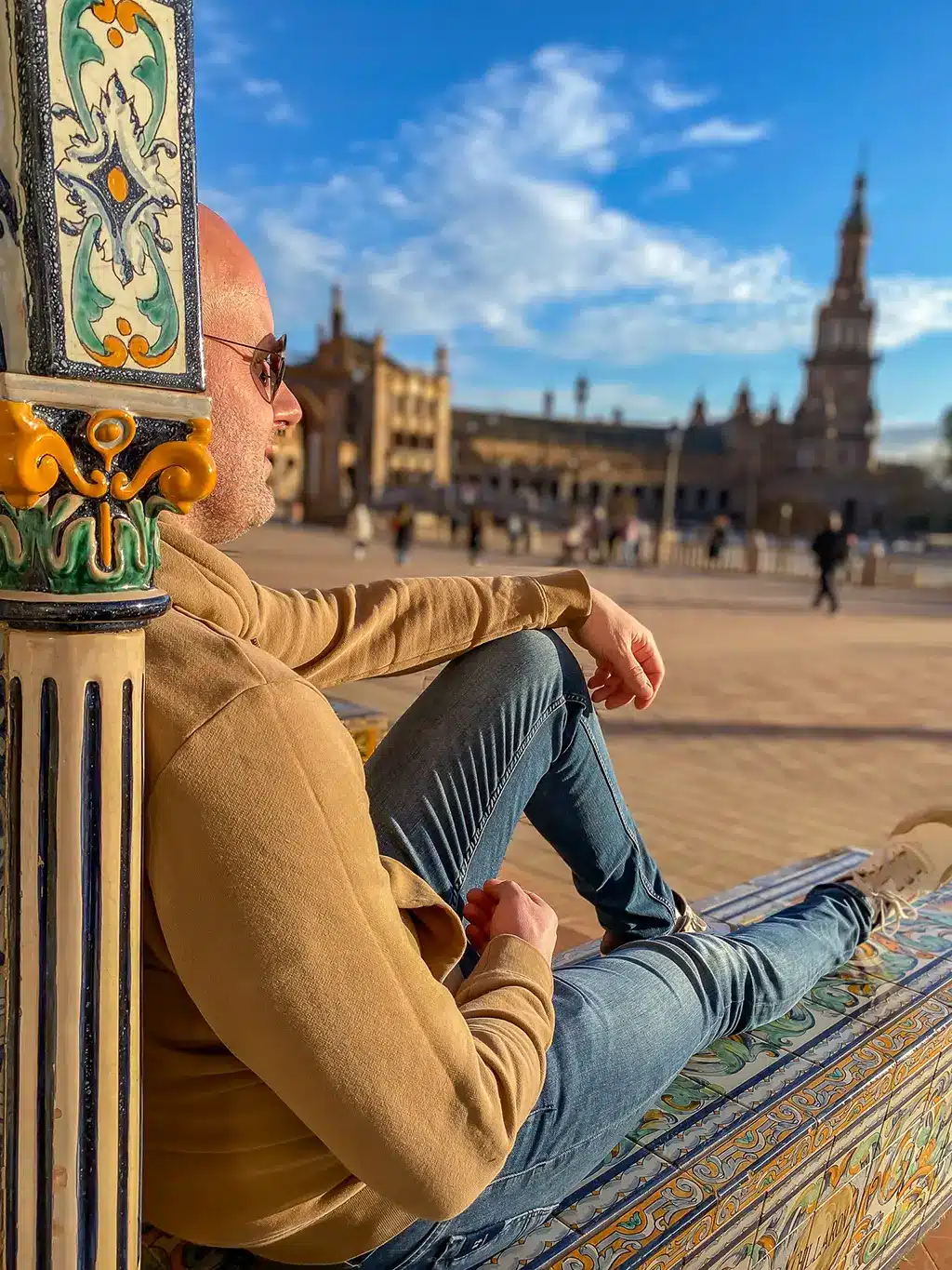 un homme assis sur un mur de mosaïques sur la place d'Espagne de Séville