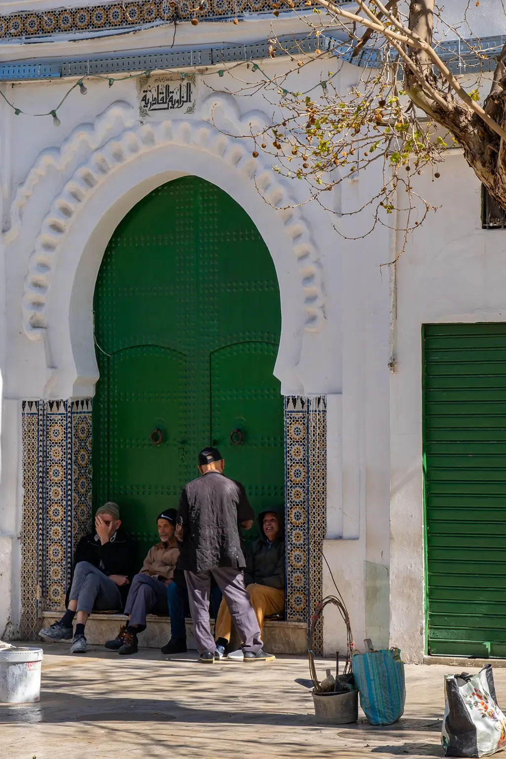 hommes discutant devant une porte verte de Tétouan