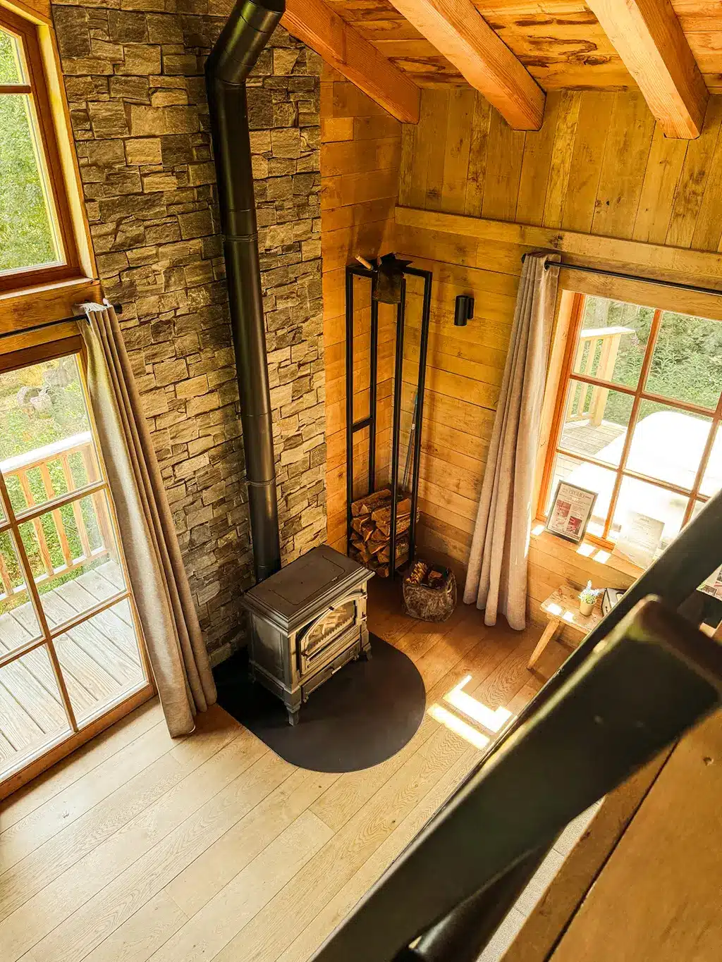 Intérieur chaleureux du Woodpecker Lodge avec poêle à bois et pierre naturelle, offrant un cadre idyllique pour un week-end romantique en Ardennes.