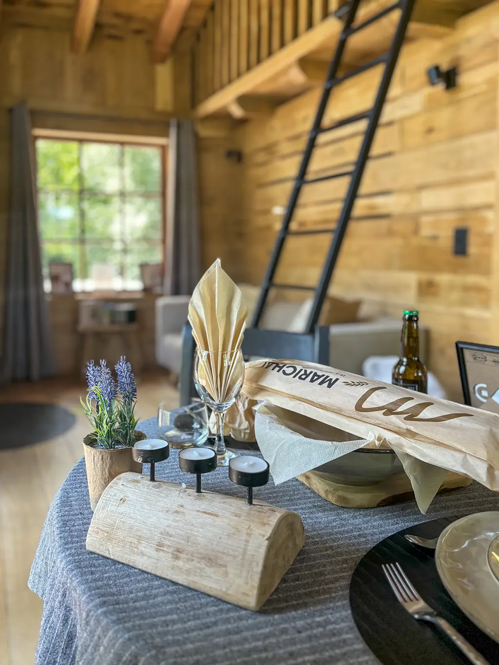 Ambiance chaleureuse à l’intérieur du Woodpecker Lodge avec table dressée pour un dîner en amoureux pendant un week-end romantique en Ardennes.