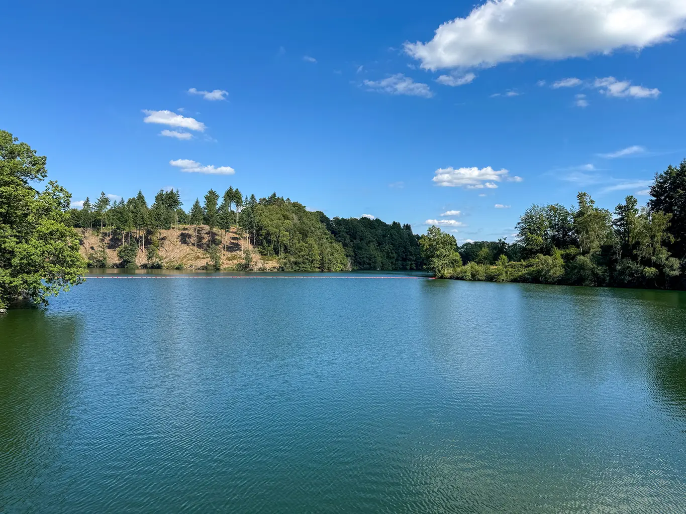 Vue paisible sur le lac de Nisramont entouré de forêts, parfaite pour une escapade nature pendant un week-end romantique en Ardennes.