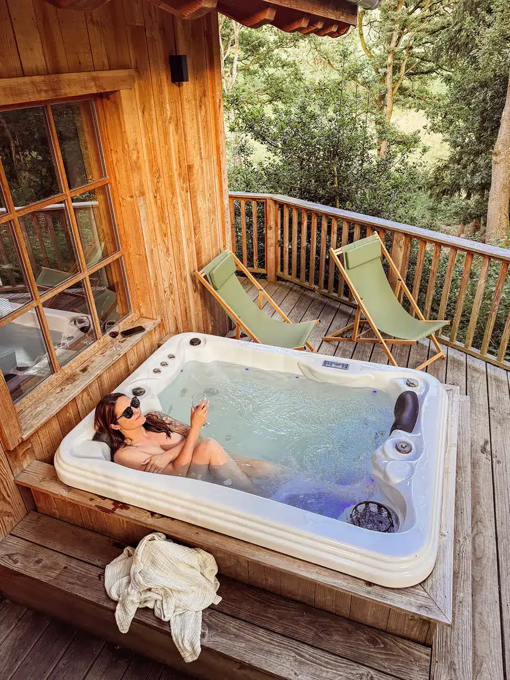Moment de détente dans un jacuzzi privatif sur la terrasse d’un chalet en bois, ambiance nature.