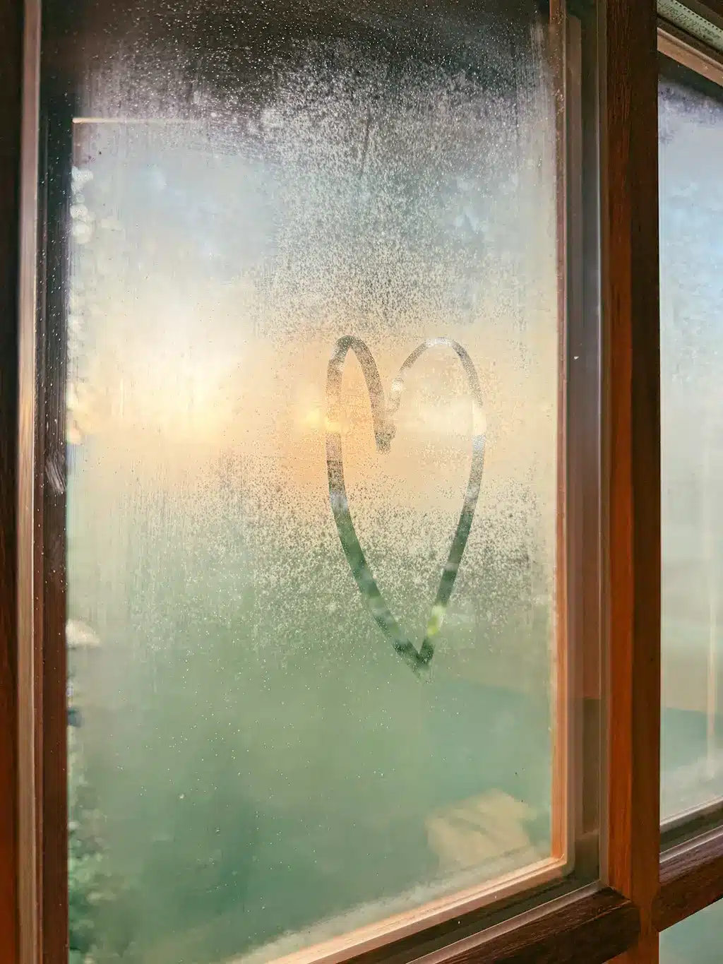 Cœur dessiné sur une fenêtre embuée, symbole de douceur et d’amour.
