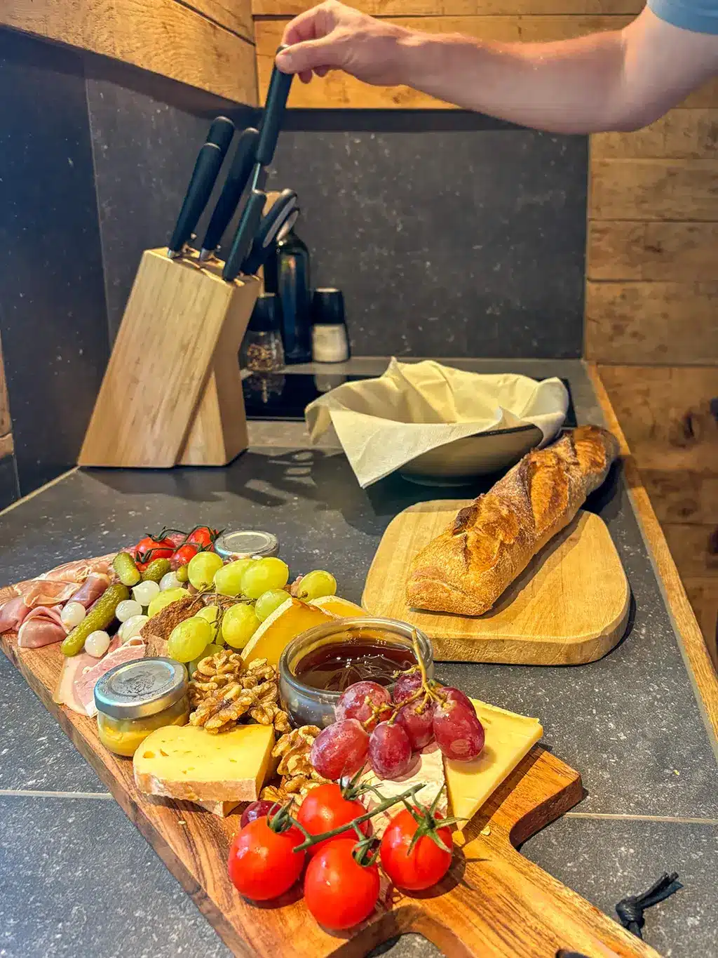 Planche apéro gourmande avec fromages, charcuterie, fruits et pain frais, parfaite pour une soirée cosy au Woodpecker Lodge pendant un week-end romantique en Ardennes.
