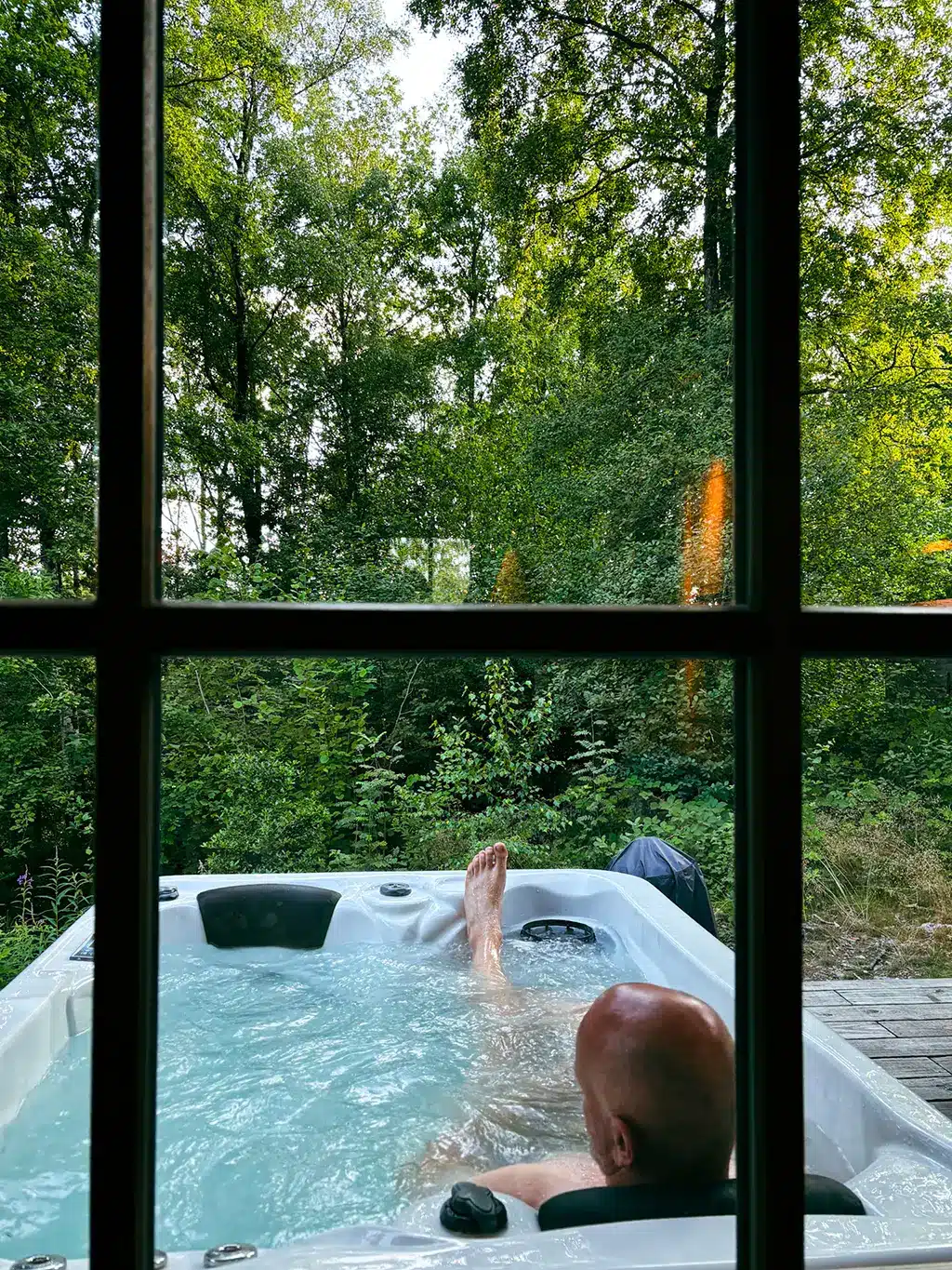Détente dans le jacuzzi privatif du Woodpecker Lodge, entouré par la forêt ardennaise, lors d’un week-end romantique.