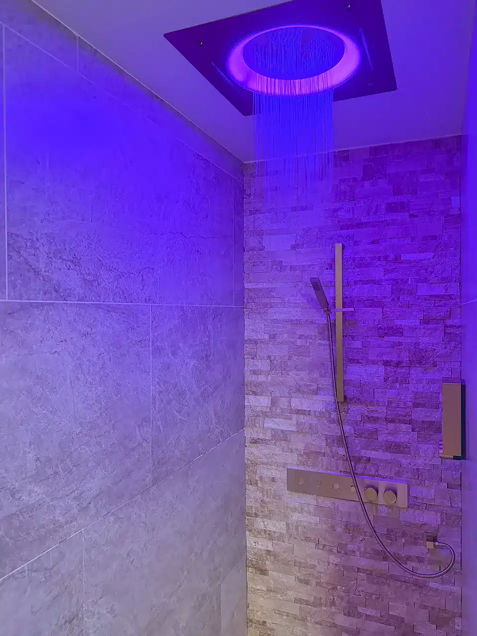 Salle de bain carrelée avec douche à effet pluie et détails dorés